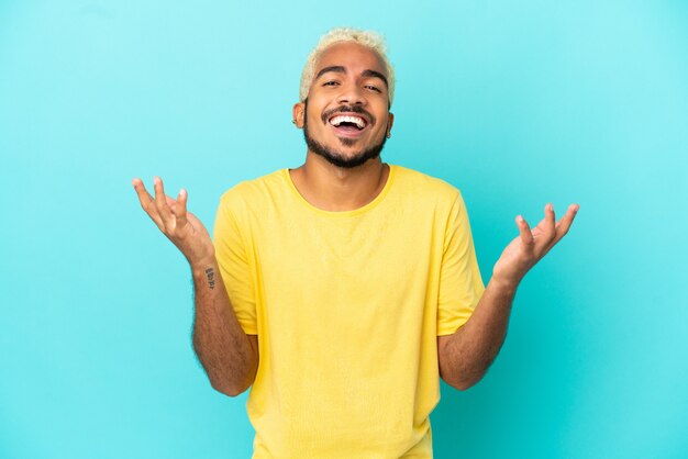 Young Colombian handsome man isolated on blue background smiling a lot