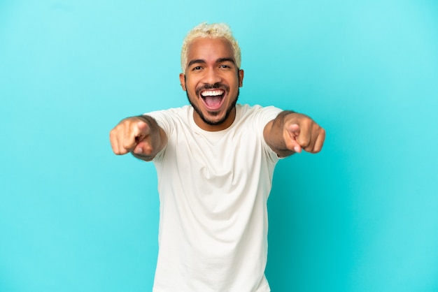 Photo young colombian handsome man isolated on blue background surprised and pointing front