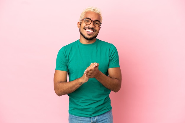 Young Colombian handsome man isolated on pink background applauding after presentation in a conference