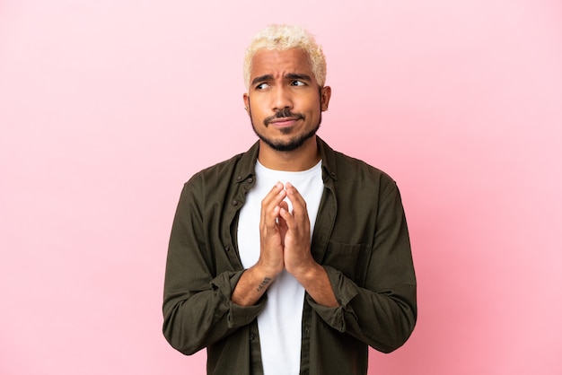 Young Colombian handsome man isolated on pink background scheming something