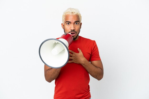 Young Colombian handsome man isolated on white background shouting through a megaphone with surprised expression