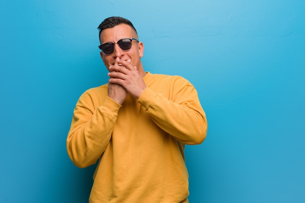 Young colombian man laughing about something, covering mouth with hands