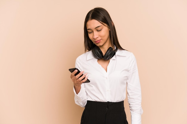 Young colombian woman listening to music with headphones and holding a phone