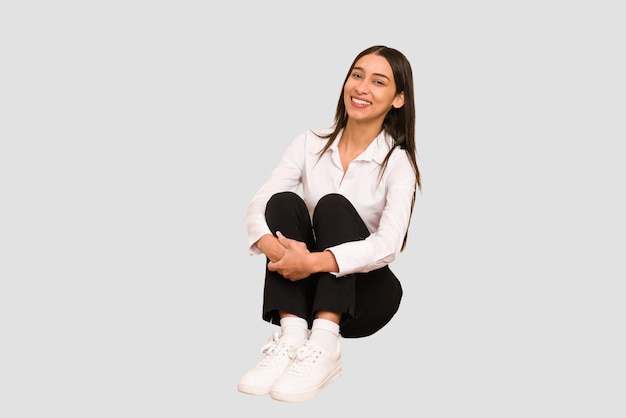 Young colombian woman sitting on the floor isolated cut out