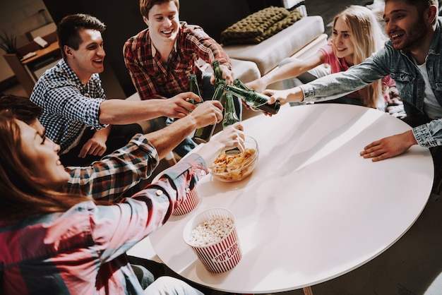 Young Company Clinking Beer Bottles On Party