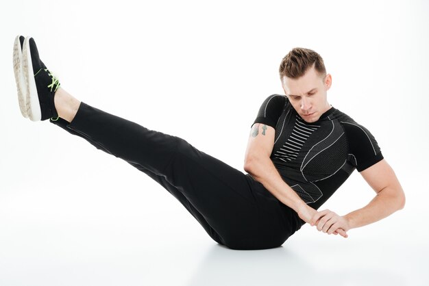 Young concentrated sportsman doing abdominal exercises on the floor