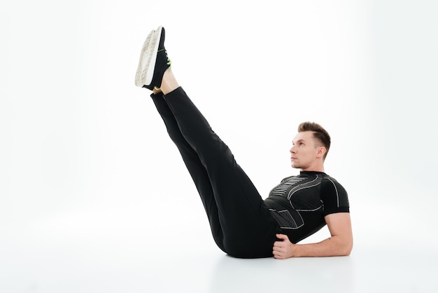 Young concentrated sportsman doing abdominal exercises on the floor