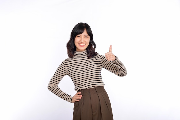 Young confident asian woman with sweater cloths showing thumb up in approval recommending standing isolated on white background