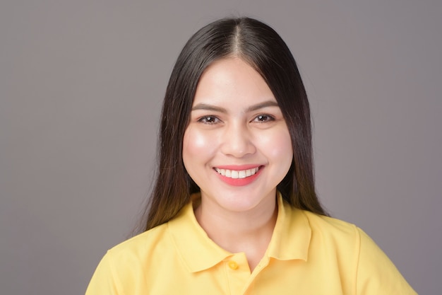 Young confident beautiful woman wearing yellow shirt is on grey background studio