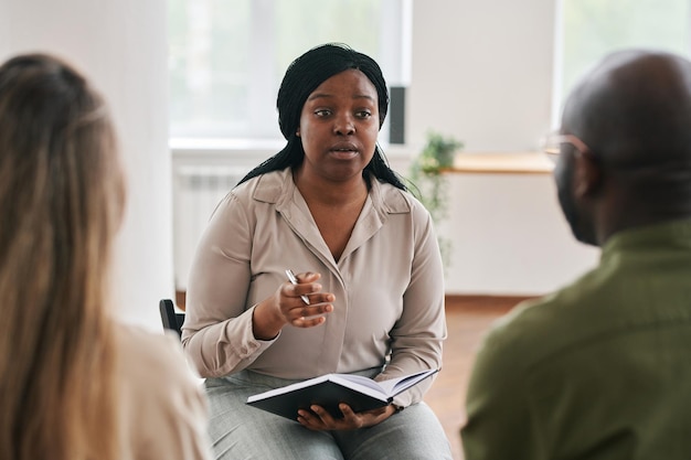 Young confident black woman with notebook and pen consulting patients