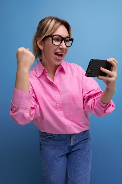 Young confident blond woman with ponytail and glasses dressed in a trendy pink shirt for the office