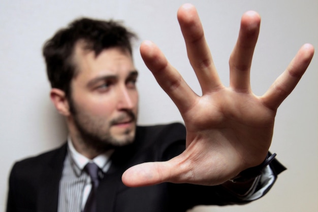 Foto giovane uomo d'affari fiducioso che mostra la mano contro il muro