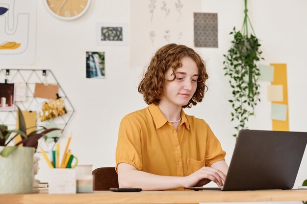 Young confident businesswoman looking through data on screen of laptop