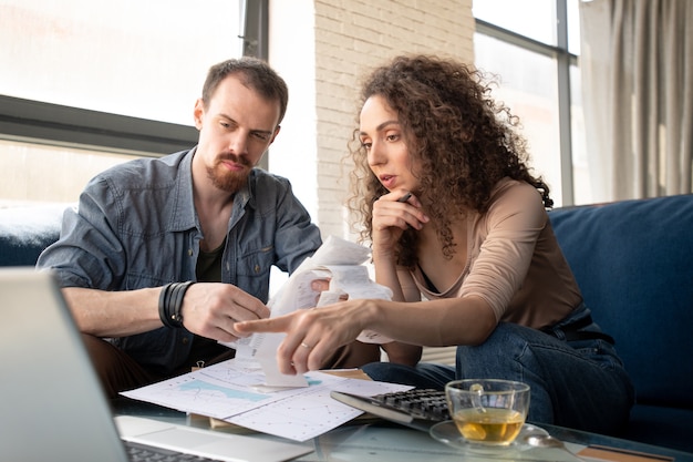 Young confident businesswoman pointing at laptop screen while making presentation of new ideas