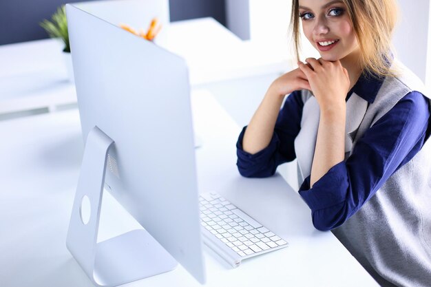 Young confident businesswoman working at office desk and typing with a laptop