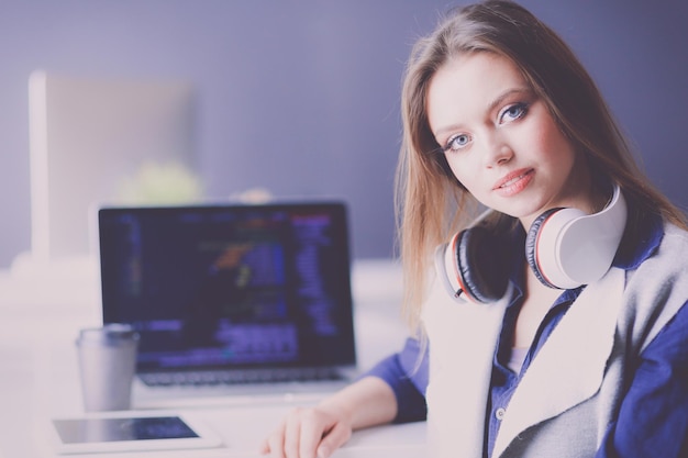 Young confident businesswoman working at office desk and typing with a laptop