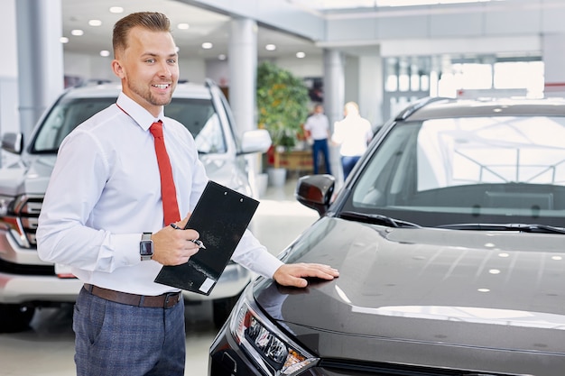 Young confident caucasian salesman discuss auto with buyers