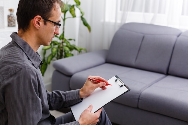 Young confident counselor with pen and document explaining something to his patient during 