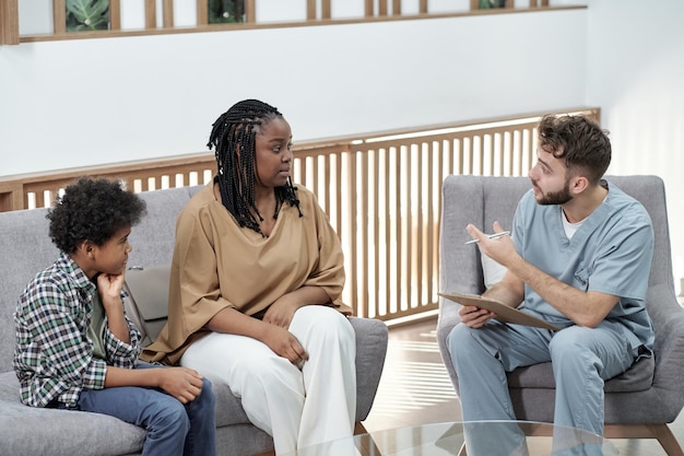 Young confident dentist giving consultation to young african woman with son