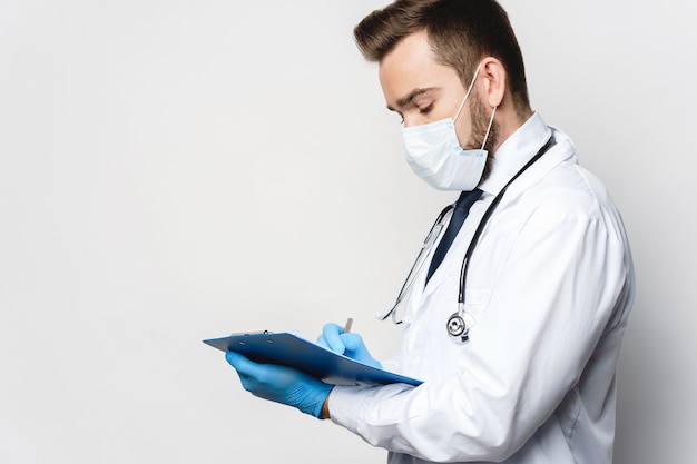 Young and confident doctor is holding the clipboard with a documents