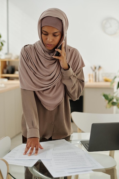 Young confident female auditor with smartphone by ear reading terms and conditions