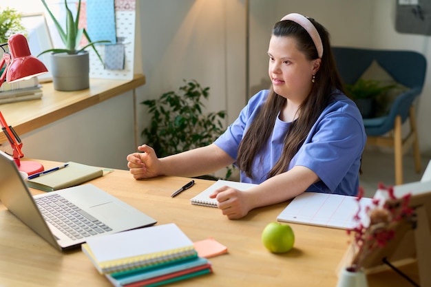 Young confident female in casualwear talking to teacher in front of laptop