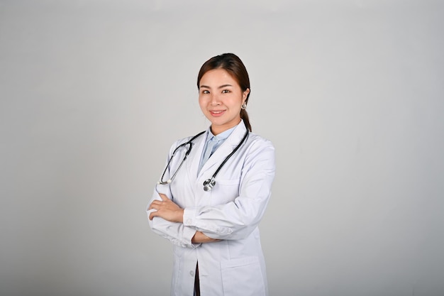 Молодая уверенная в себе женщина-врач, стоящая на белом изолированном фоне