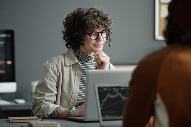 Young confident female IT support manager listening to online client