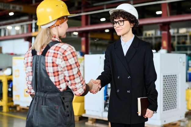 Young confident female manager shaking hand of engineer after making agreement