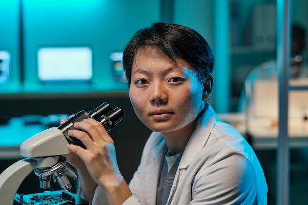 Young confident female scientist or technician with microscope