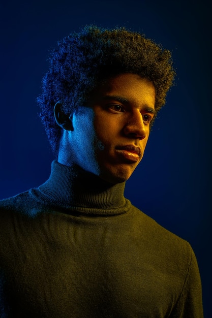 Young confident man in sunglasses, cool guy posing for camera studio shot over dark background