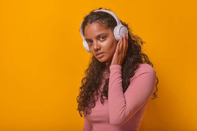 Young confident pretty indian woman in wireless headphones stands in studio