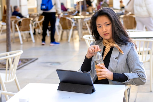 Young confident smiling Asian business woman sitting on busy street portrait