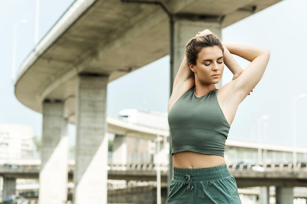 Young and confident woman athlete is warming up before her street workout