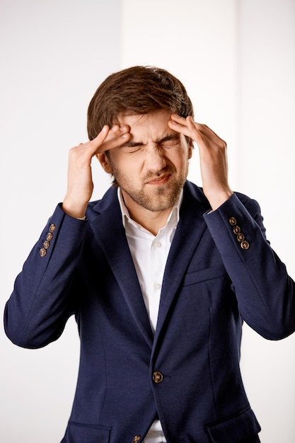 Young confused businessman standing near the office desk and hol