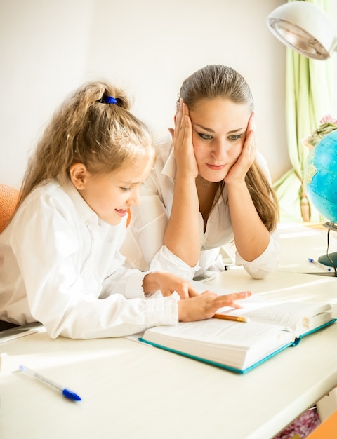 Giovane madre confusa che guarda i compiti delle figlie