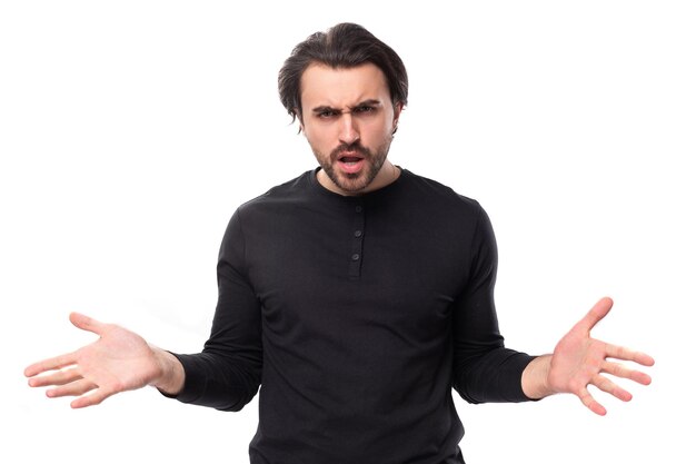 Young confused pleasant brunette man in a black sweater on an isolated white background