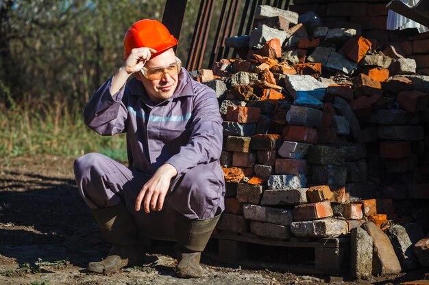 Young construction worker in an orange helmet and protective glasses