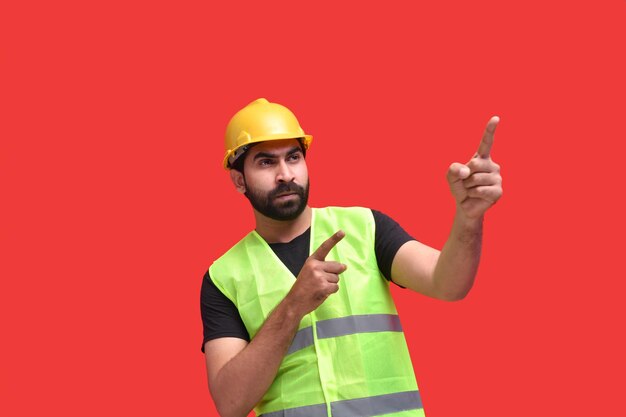 young construction worker wearing safety vest and pointing up indian pakistani model