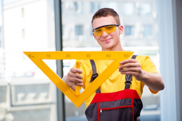 Young construction worker in yellow coveralls