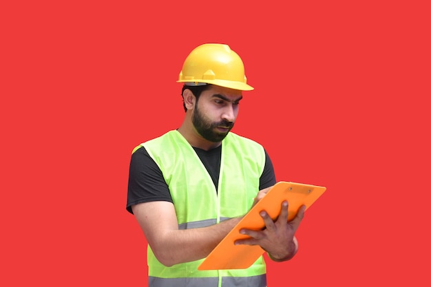 クリップボードのインドのパキスタンのモデルに書いている若い建設労働者