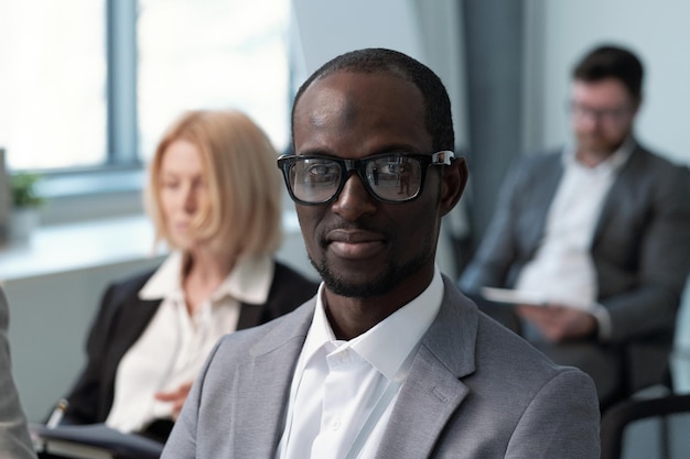 Young contemporary black man in formalwear and eyeglasses looking at camera