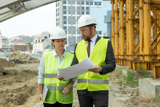 Young contemporary builders discussing sketch on blueprint