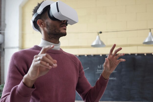 Young contemporary businessman in virtual reality headset preparing or looking through online presentation