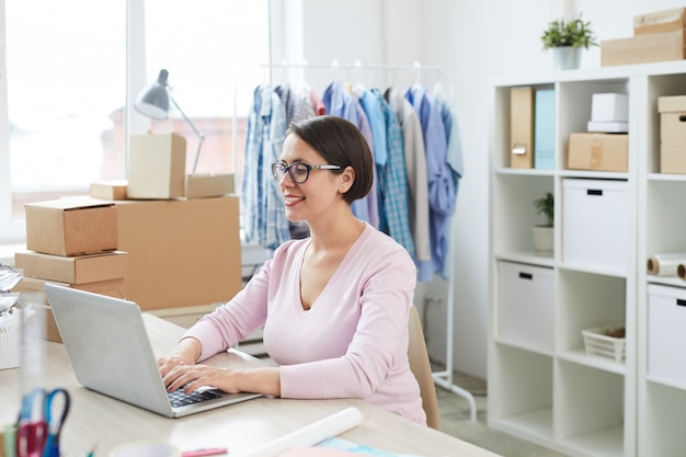 Young contemporary female customer with laptop making online order