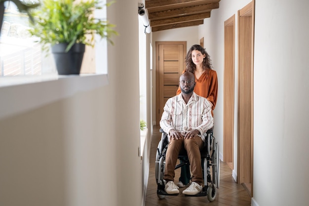 Young contemporary interracial couple standing in corridor of apartment