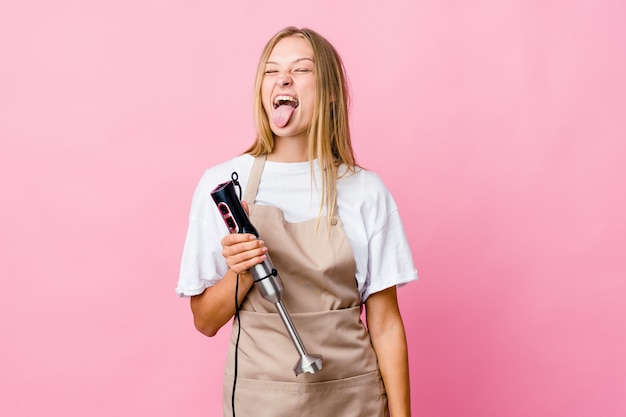 Young cook woman holding an electric mixer isolated