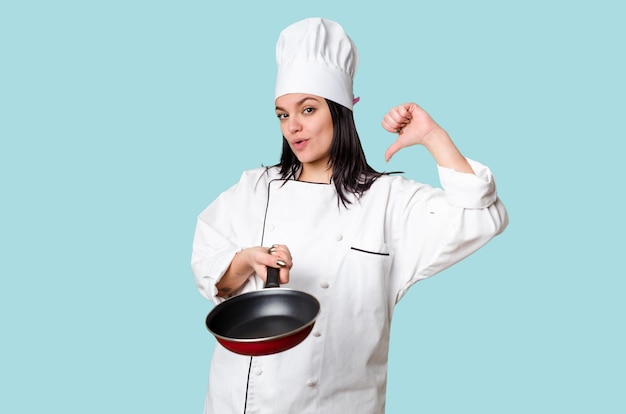 Young cook woman holding a frying pan isolated