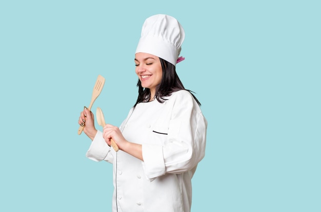 Young cook woman holding wooden spoon and fork isolated