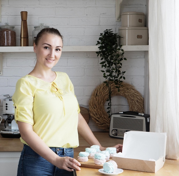 Young cook woman packs pastries in a box Small home business